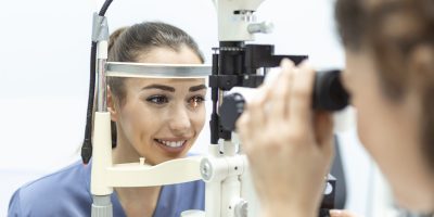 Eye doctor with female patient during an examination in modern clinic. Ophthalmologist is using special medical equipment for eye health