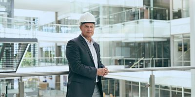 Portrait of a confident professional male architect standing next to the development site while looking at the camera inside a building.